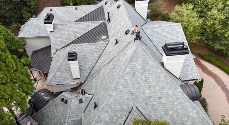 Finished slate-look designer shingle roof with metal-clad dormers and chimney flashing