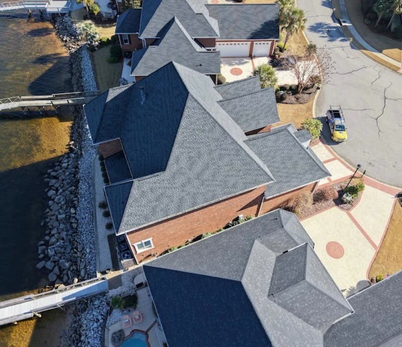 Waterfront homes with newly completed shingle roofs seen from above