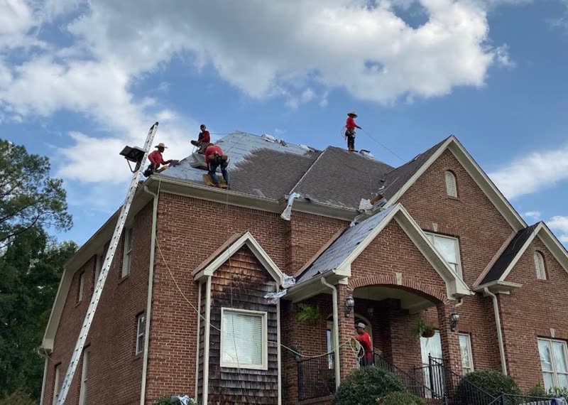 Crew stripping old shingles from a brick two-storey home