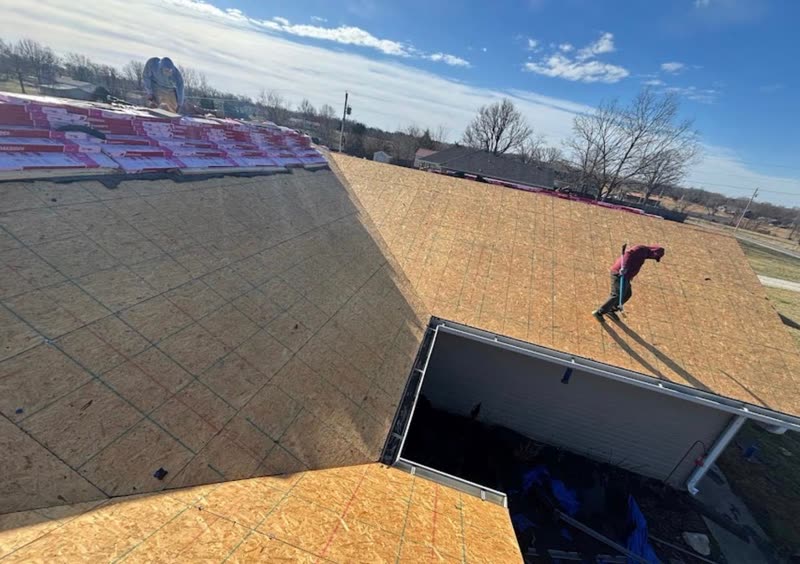 Roof stripped to bare decking with shingle bundles staged along the ridge